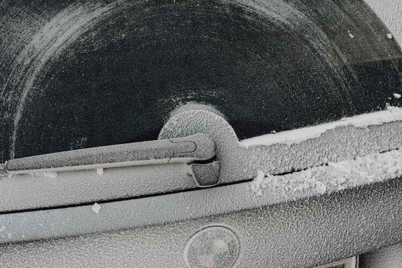 A car window covered in a thin layer of snow and ice