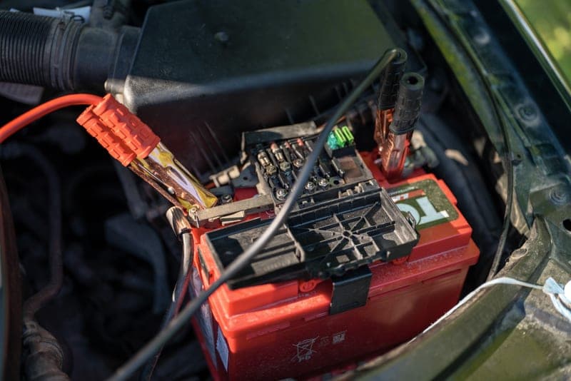 A car battery under the hood, of the kind a maintainer keeps charged - a stand-in for the NOCO GENIUS1 1A Smart Charger and Maintainer, not a photograph of this model