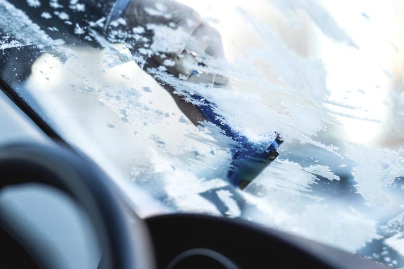 Ice being cleared from a car windshield - a stand-in for the Rain-X De-Icer Windshield Washer Fluid, not a photograph of this model